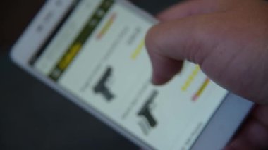 Bir adam arıyor ve sitede satın almak için bir silah seçer.