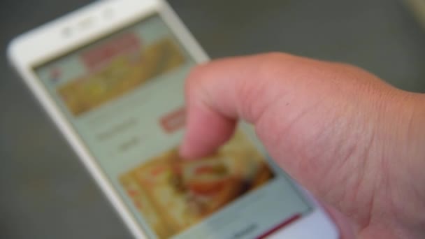 Ein Mann sucht und wählt Pizza auf dem Smartphone — Stockvideo
