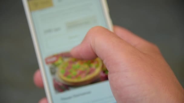 Een man op zoek en kiest pizza op smartphone — Stockvideo