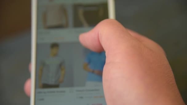 Hombre buscando y elige la ropa en el teléfono inteligente — Vídeos de Stock