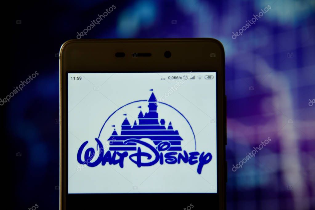 Ivano-Frankivsk, Ukraine - May 13, 2019: Walt Disney logo is seen on an smartphone over stock chart. Walt Disney logo is displayed on the screen of a mobile device.