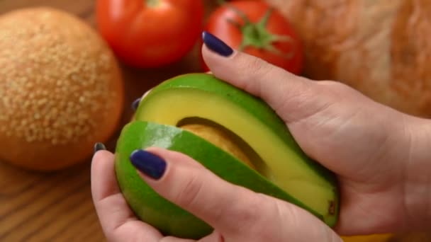 Frau öffnet eine Avocado in zwei Teilen — Stockvideo