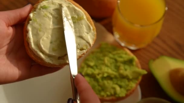 Vrouw verspreiden romige kaas op avocado toast — Stockvideo