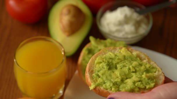 Жінка розпускає вершковий сир на тості авокадо — стокове відео