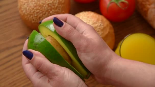 Женщина открывает авокадо в двух частях — стоковое видео