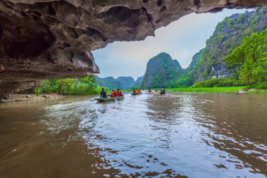 Turistler, sivil toplum örgütü Dong Nehri boyunca tekne seyahat ve Tam Coc resim çekmek itmek için ayak kullanarak kürekçi kürek, Tam Coc, Ninh Binh, Vietnam.