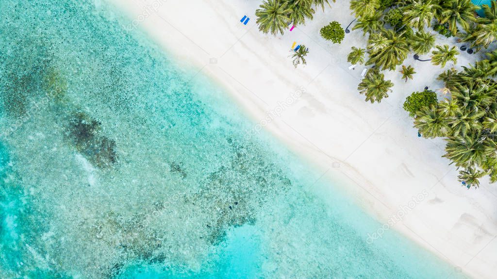 Aerial top view tropical island white sand beach with blue lagoon sea sky in Maldives island, Beautiful tropical maldives resort hotel.