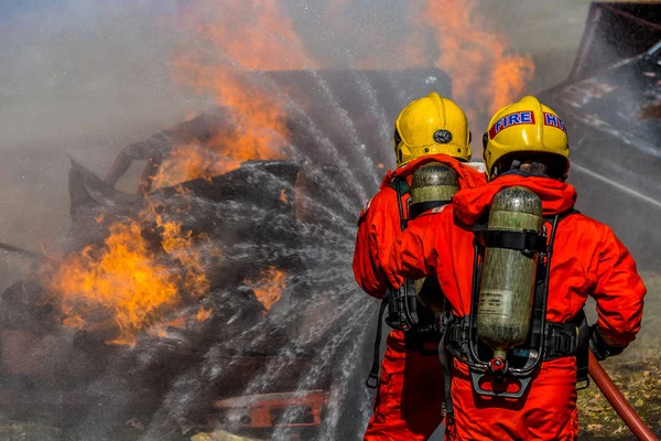 Firefighter in fire fighting operation, Firefighter using extinguisher and water from hose for fire fighting.