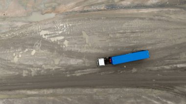 Toprak yolda hava görüntüleme kamyoneti, toprak yolda karavanı olan yarı kamyonet, toprak yolda giden yarı kamyon kargosunun üst görüntüsü..