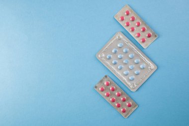 Blister paketleri mavi zemin üzerine mavi ve pembe hap boşaltmak-sağlık ve tıp kavramı ile çapraz olarak düzenlenmiş