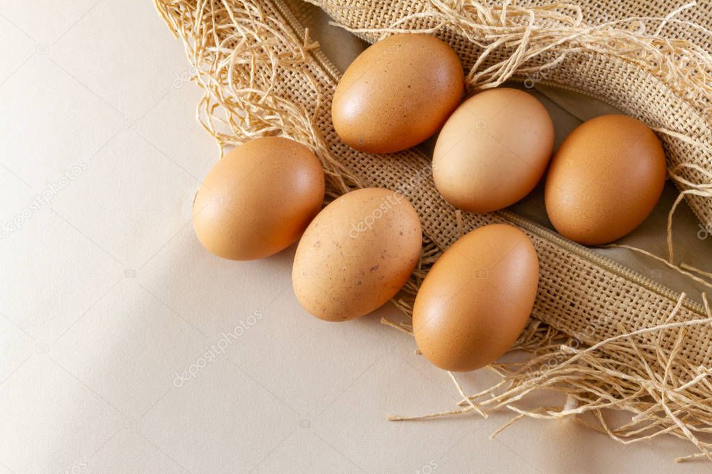 Six eggs on a brown sackcloth (burlap) and white background- traditional organic food concept demonstration