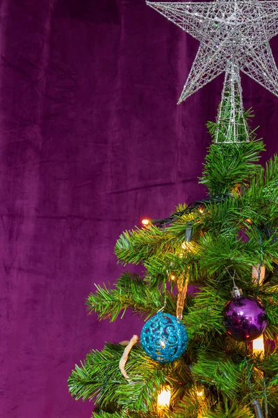 トップ 装飾的なハンギング ボールとキャンドル ライトで著名なスターが紫色のテーマで装飾されたクリスマス ツリー — ストック写真