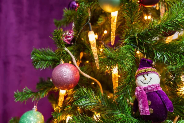 著名な紫雪だるまと装飾的な紫色のボールと目の前でキャンドル ライトが紫色のテーマで装飾されたクリスマス ツリー — ストック写真