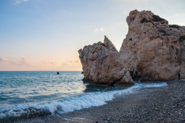Petra tou Romiou, Paphos, Kıbrıs için çevresinde çakıllı plaj dalgalar breaking öğleden sonra Görünüm. Yunan mitolojisinde Afrodit'ın Doğum yeri olarak kabul edilir.