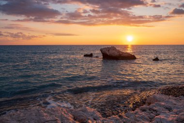 Beach çevresinde Petra tou Romiou, Paphos, Kıbrıs için güzel gün batımı manzarası. Yunan mitolojisinde Afrodit'ın Doğum yeri olarak kabul edilir.