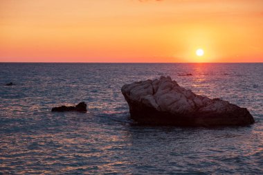 Beach çevresinde Petra tou Romiou, Paphos, Kıbrıs için güzel gün batımı manzarası. Yunan mitolojisinde Afrodit'ın Doğum yeri olarak kabul edilir.