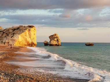 Paphos, Kıbrıs - 24 Kasım 2018: İnsanlar kendilerini Petra tou Romiou içinde banyo öğleden sonra ışık, Paphos, Kıbrıs'ta kayalar karşı sahilde tadını çıkarın. Plaj Yunan mitolojisinde Afrodit'ın Doğum yeri olarak kabul edilir.