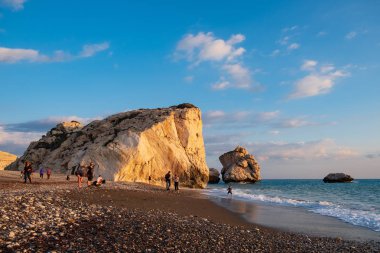 Paphos, Kıbrıs - 24 Kasım 2018: İnsanlar kendilerini Petra tou Romiou içinde banyo öğleden sonra ışık, Paphos, Kıbrıs'ta kayalar karşı sahilde tadını çıkarın. Plaj Yunan mitolojisinde Afrodit'ın Doğum yeri olarak kabul edilir.