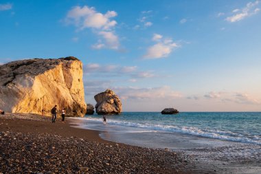 Paphos, Kıbrıs - 24 Kasım 2018: İnsanlar kendilerini Petra tou Romiou içinde banyo öğleden sonra ışık, Paphos, Kıbrıs'ta kayalar karşı sahilde tadını çıkarın. Plaj Yunan mitolojisinde Afrodit'ın Doğum yeri olarak kabul edilir.