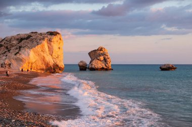 Paphos, Kıbrıs - 24 Kasım 2018: İnsanlar kendilerini Petra tou Romiou içinde banyo öğleden sonra ışık, Paphos, Kıbrıs'ta kayalar karşı sahilde tadını çıkarın. Plaj Yunan mitolojisinde Afrodit'ın Doğum yeri olarak kabul edilir.