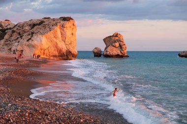 Paphos, Kıbrıs - 24 Kasım 2018: Bir çocuk sahilde Petra tou Romiou kayalar, Paphos, Kıbrıs için oynamaktadır. Plaj Yunan mitolojisinde Afrodit'ın Doğum yeri olarak kabul edilir.