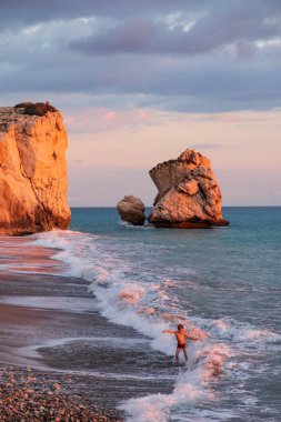 Paphos, Kıbrıs - 24 Kasım 2018: Bir çocuk sahilde Petra tou Romiou kayalar, Paphos, Kıbrıs için oynamaktadır. Plaj Yunan mitolojisinde Afrodit'ın Doğum yeri olarak kabul edilir.