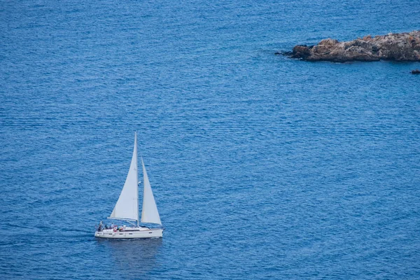 Aerial view of a sailing boat in the Mediterranean Sea as seen from Aphrodite hiking trail in Akamas peninsula, Cyprus
