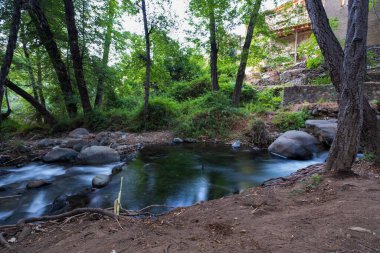 Kıbrıs 'ın Troodos kentindeki Kakopetria ormanındaki kayalık dağ arazisinden akan saf su akıntısı. Yavaş maruz kalma gerçek akış izi oluşturur.