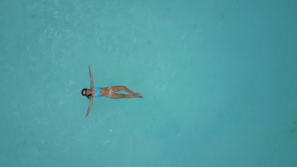 Aerial: a girl in a bathing suit prohlozhdaet at sea, lies in the ocean. — Stock Video