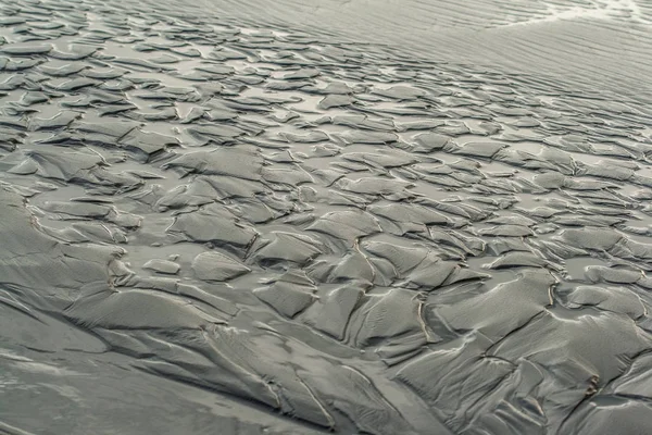 Retreating waves leave patterns in the sand on a beach in Olympic National Park