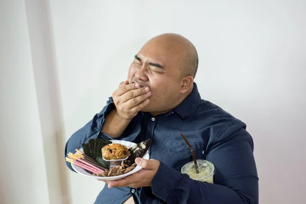 fat man eating, portrait of overweight person feels hungry and eating chips,cake,green tea frappe seated on armchai, isolated on white background with clipping path