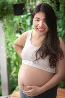 Hamile bir kadın çocuğuna bakarken kendini mutlu hissediyor. Doğum öncesi bakım ve kadın hamileliği konsepti.