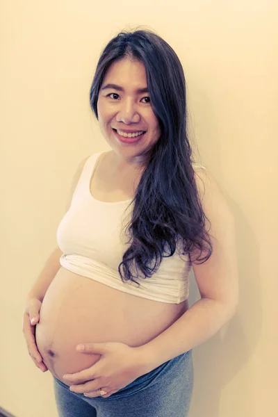 Ciężarna kobieta czuje się szczęśliwa w domu podczas opieki nad dzieckiem. Opieka prenatalna macierzyństwa i koncepcja ciąży kobiet. — Zdjęcie stockowe