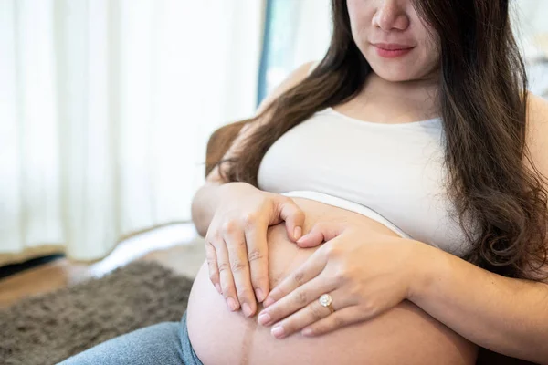 Ciężarna kobieta czuje się szczęśliwa w domu podczas opieki nad dzieckiem. Opieka prenatalna macierzyństwa i koncepcja ciąży kobiet. — Zdjęcie stockowe