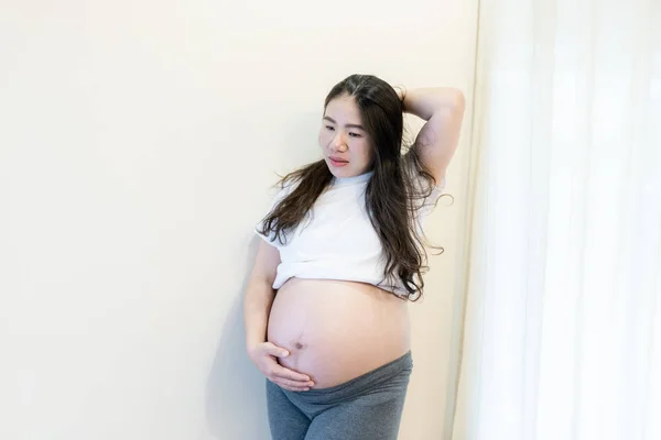 Gravid kvinna känner sig lycklig hemma när hon tar hand om sitt barn. Begreppet mödravård och kvinnlig graviditet. — Stockfoto