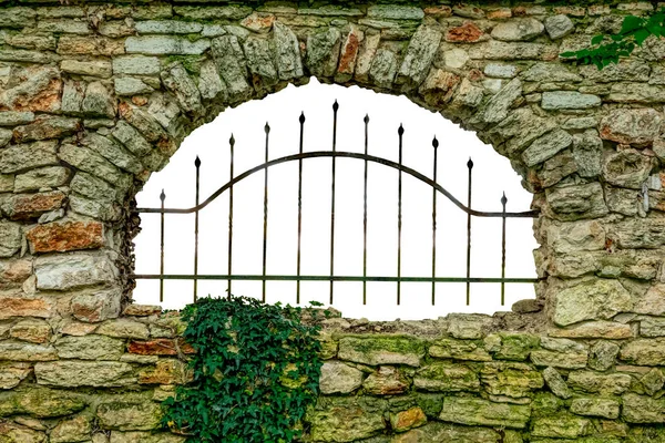 An old stone wall with a metal grille on the opening. White background.