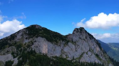 Tegernsee Htte 'nin 4K hava aracı videosu. Güneşli bir günde Leonhardstein' ı çevreleyen Alman Alpleri 'ndeki Rostein ve Buchstein tepeleri arasındaki dağlarda yuva yapmış inanılmaz bir kulübe.