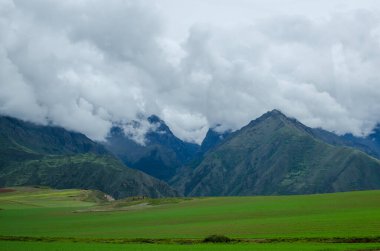 Bir dağ manzarasının stok fotoğrafı. Gökyüzü bulutlu. Arka planda dağların tepesinde kar var..