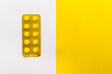 Beyaz, sarı, beyaz ve beyaz arka planda sarı kabarcık ambalajlı hapların stok fotoğrafı. Resimde kimse yok..