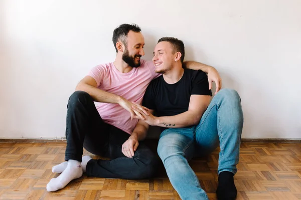彼らのアパートで笑っている2人の白人同性愛者の男性のストック写真 彼らの一人は背後からもう一人を抱き上げている — ストック写真