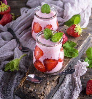 taze çilek ve gri bir ahşap tahta üzerinde bir cam kavanoza yoğurt smoothies