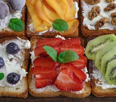Fransız tost yumuşak peynir, çilek, kivi, ceviz ve yaban mersini kahverengi ahşap tahtası, üstten görünüm