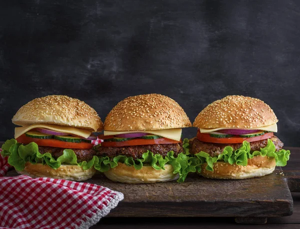 Sığır eti, peynir ve rustik ahşap kahverengi kesme tahtası, closeup sebze ile hamburger