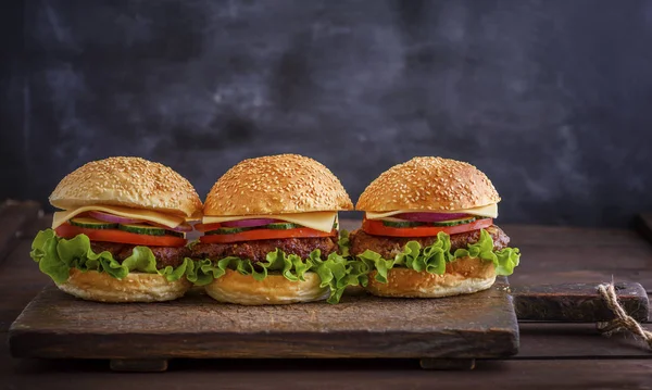 Ev yapımı hamburger sığır eti, soğan, domates, marul, peynir ve baharatlar ile. Taze hamburger closeup ahşap rustik kesme tahtası, kopya alanı üzerinde