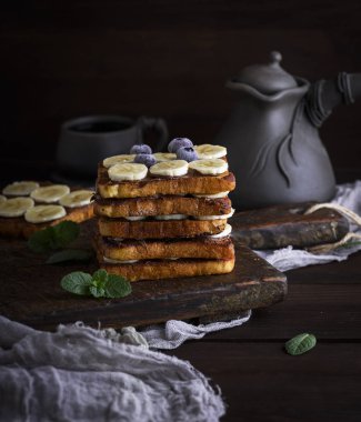 beyaz ekmek, çikolata ve muz dilimleri ortasında bir kahverengi ahşap tahta üzerinde bir yumurtalı ekmek tost kare parçaların büyük bir sandviç