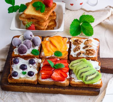 Fransız tost yumuşak peynir, çilek, kivi, ceviz, kiraz ve yaban mersini kahverengi ahşap tahtası, üstten görünüm