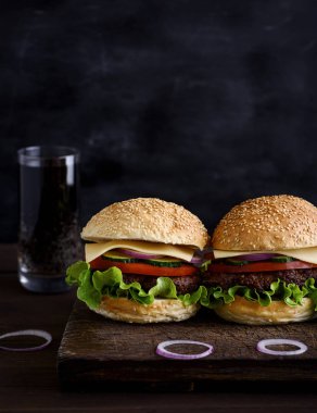 et, sebze ve peynir ile iki hamburger, buğday unu ile susam, içki cam arkasında yuvarlak bisküvi yapılmış