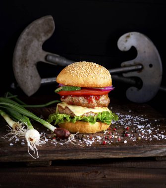 sebze ve peynir, taze beyaz buğday unu ile susam, tuz ve biber, arkasında bir et bıçağı ile kahverengi bir gemide bir sandviç ile duble burger