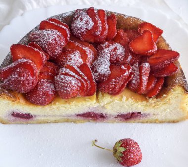 yarım bir çilekli cheesecake beyaz seramik plaka, üstten görünüm