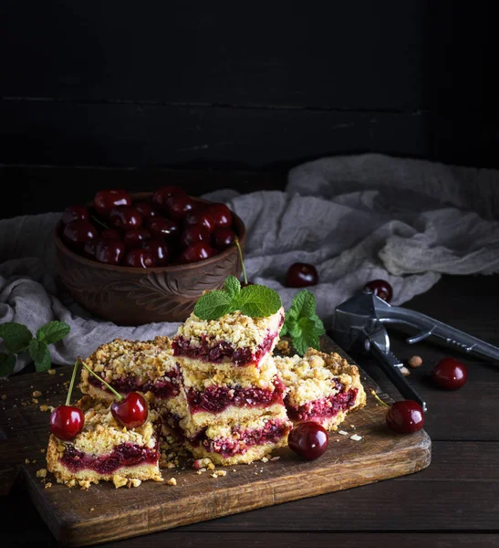 kiraz ve seramik kase taze çilek, siyah arka plan ile pişmiş kek yığını